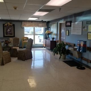 A spacious and well-lit waiting area in a healthcare facility, featuring comfortable seating and decorative plants.