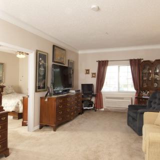 A cozy living room with elegant furnishings, featuring a television and decorated with framed artwork.