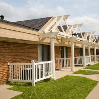 A row of brick apartment units with small terraces and white railings.