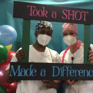 Healthcare workers celebrating the impact of vaccinations with a fun photo frame.