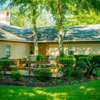 A quaint house with a wooden deck surrounded by lush greenery and trees.