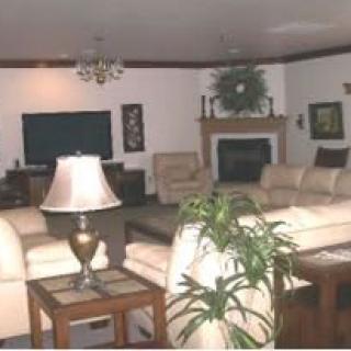 A spacious living room with cream-colored sofas, a central fireplace, and decorative plants.