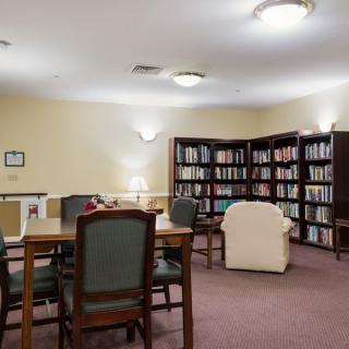 A quiet library room with bookshelves, tables, and chairs for reading.
