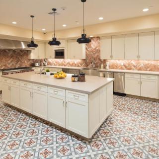 A spacious modern kitchen with an island and decorative tile flooring.