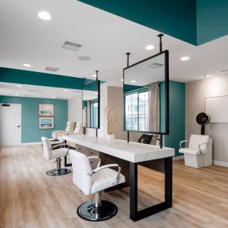 A modern and stylish hair salon interior with sleek design elements, featuring large mirrors, comfortable chairs, and wooden flooring.