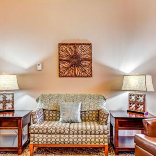 A cozy living room features a patterned sofa with two side tables and matching lamps, complemented by a decorative wall piece.