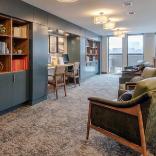 A modern and cozy living room with bookshelves and a workspace area.