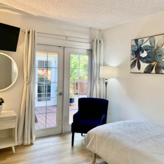 A serene and modern bedroom featuring a comfortable bed, stylish seating, and ample natural light.
