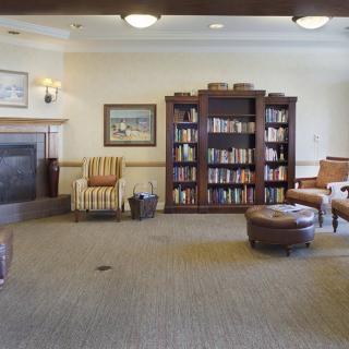 A cozy library with a bookshelf, fireplace, and comfortable seating.