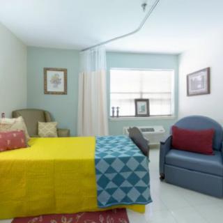 A bright and colorful bedroom with a vibrant bedspread, comfortable armchair, and framed artwork.