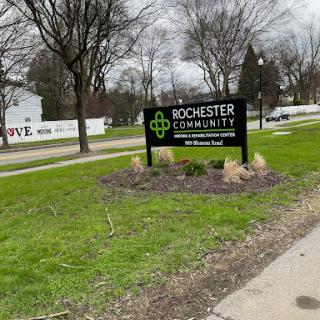 A community sign for Rochester, surrounded by grassy areas and trees.