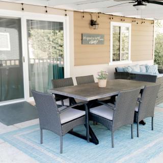 A cozy outdoor patio setup with a rattan dining set and string lights.
