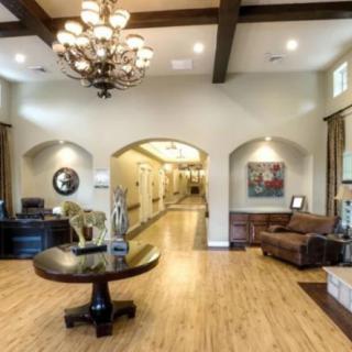 Spacious and elegant lobby with a chandelier, wooden flooring, and comfortable seating.