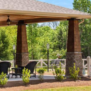 A cozy outdoor gazebo with seating surrounded by lush greenery.