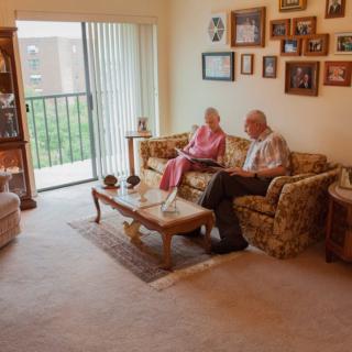An elderly couple sitting together on a sofa in a cozy living room.