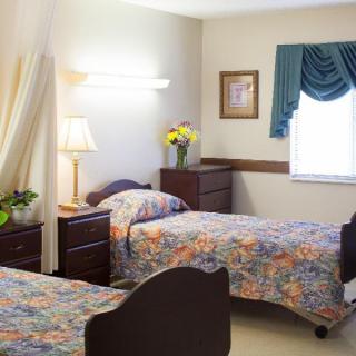 A shared bedroom with two single beds, a lamp, and floral decor.
