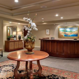 A warmly decorated reception area featuring a wooden table with floral centerpiece and framed artwork on the wall.