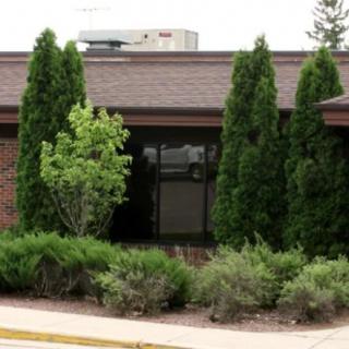 A view of a building surrounded by greenery, including shrubs and trees.