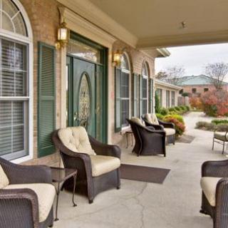 A cozy porch with wicker chairs and decorative windows, leading to the entrance of a building.