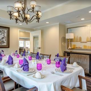 An elegantly set dining room table with purple napkins and stylish decor.