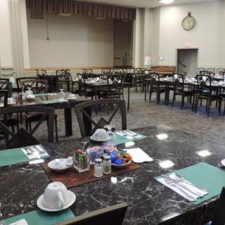 An empty dining hall with neatly arranged tables and chairs.