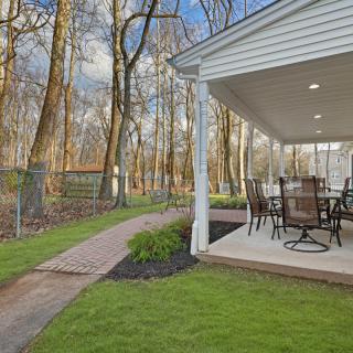 A cozy outdoor patio with seating, adjacent to a lush green lawn and wooded area.