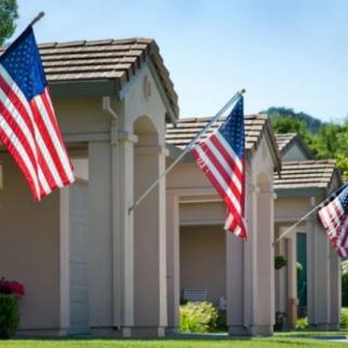 Suburban homes displaying American flags on a sunny day.
