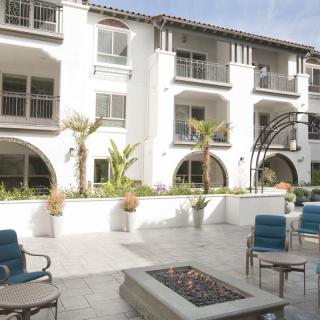A modern apartment complex with an outdoor seating area and a central fire pit.