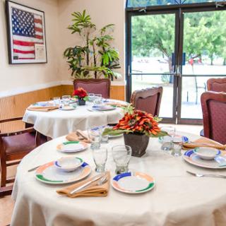 A well-decorated dining area featuring elegantly set tables with floral arrangements and an American flag on the wall.