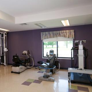 A gym room featuring various exercise equipment and a purple accent wall.