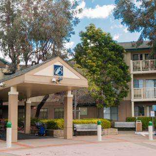 A hotel building with a covered entrance surrounded by trees.