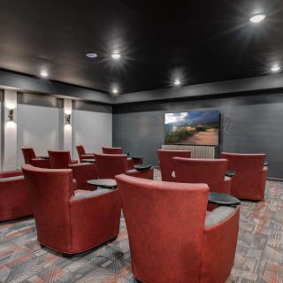 A modern home theater with red swivel chairs facing a large screen.