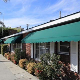 A brick building with green awnings lining a sunny sidewalk.