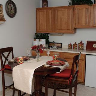 A cozy dining area with a neatly set table and wooden kitchen cabinets.
