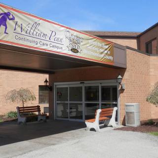 Entrance to a nursing care center with benches and signage.