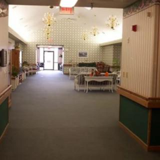 A spacious hallway with tables and chairs, featuring decorative light fixtures and carpeted flooring.
