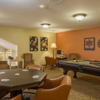 A cozy game room featuring a pool table and a cards table with comfortable seating.