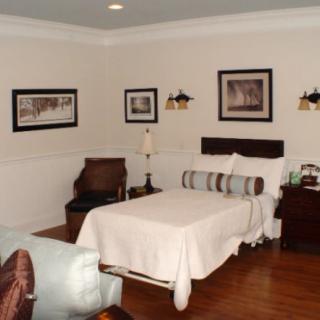 A cozy bedroom with a neatly made bed, stylish lamps, and framed wall art.