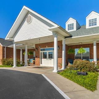 A sunny day view of a building entrance with columns and landscaping.