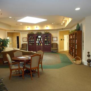 A cozy library setting with bookshelves, a seating area, and a table with chairs.