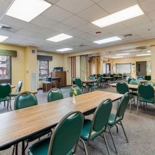 A spacious conference room with tables and green chairs arranged for meetings.