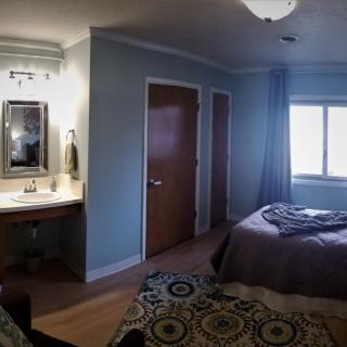 A cozy bedroom with a bed, mirror, and window.