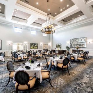 A spacious and elegantly designed dining room with neatly arranged tables and a large chandelier.