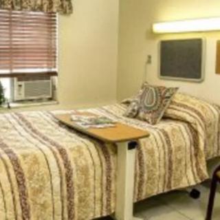 A hospital room with a neatly made bed and bedside table.