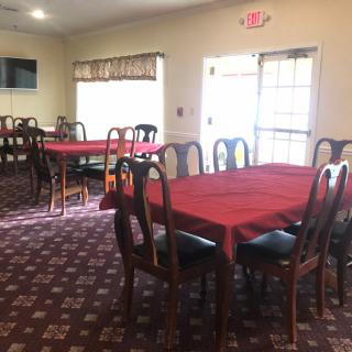 A dining room with tables covered in red tablecloths and chairs arranged neatly.
