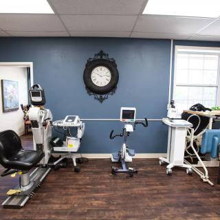 A physical therapy room equipped with various rehabilitation machines and an exercise bike.