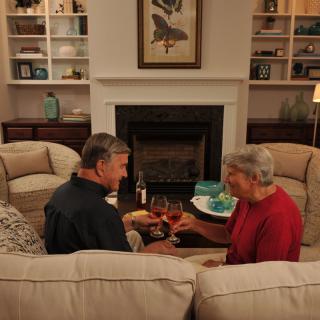Two people enjoying a cozy evening with wine in a warmly decorated living room.