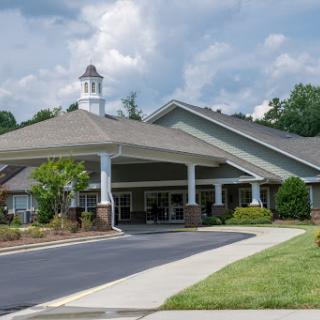 A welcoming entrance to a senior living community, featuring landscaped grounds and a modern architectural design.