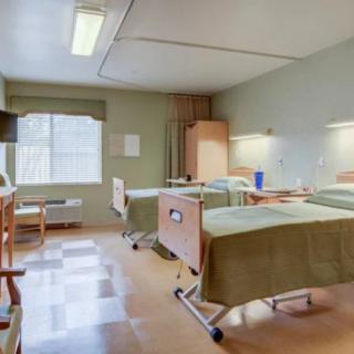 A clean and well-organized hospital room with two beds and a large window.