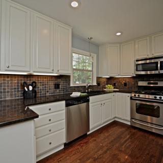 A modern kitchen with white cabinets and stainless steel appliances.